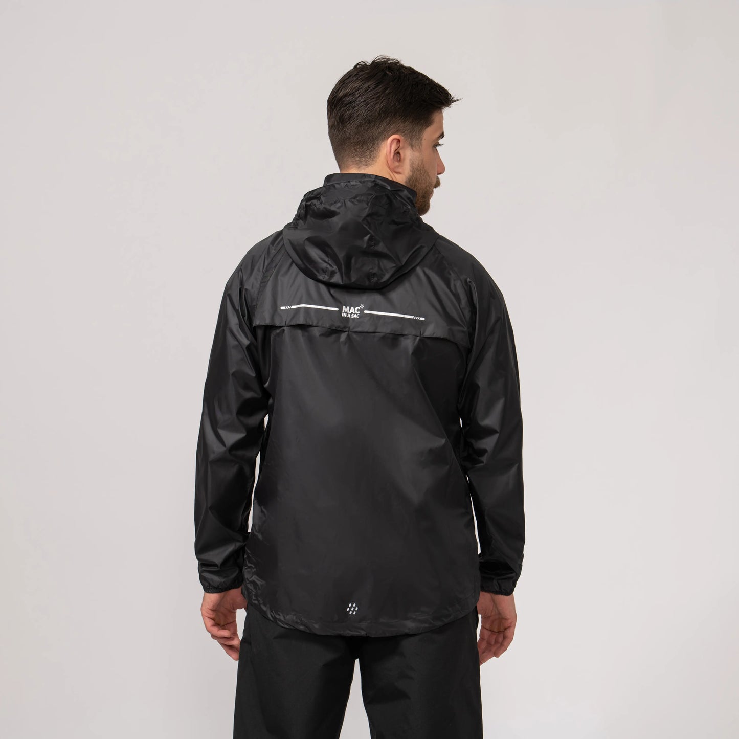 Person wearing a black waterproof and windproof rain jacket showing the back side with a visible brand logo on a light gray background