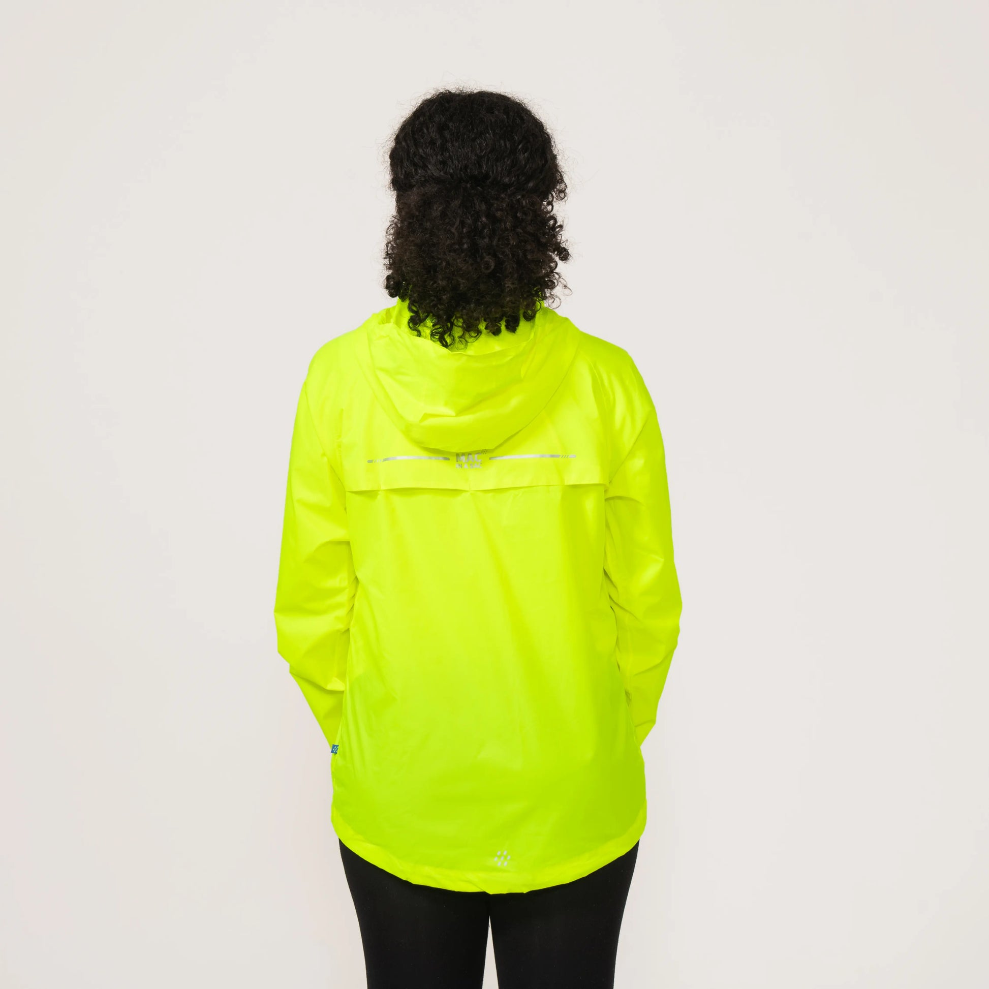 Person wearing a bright neon yellow waterproof and windproof rain jacket displaying the back on a plain background