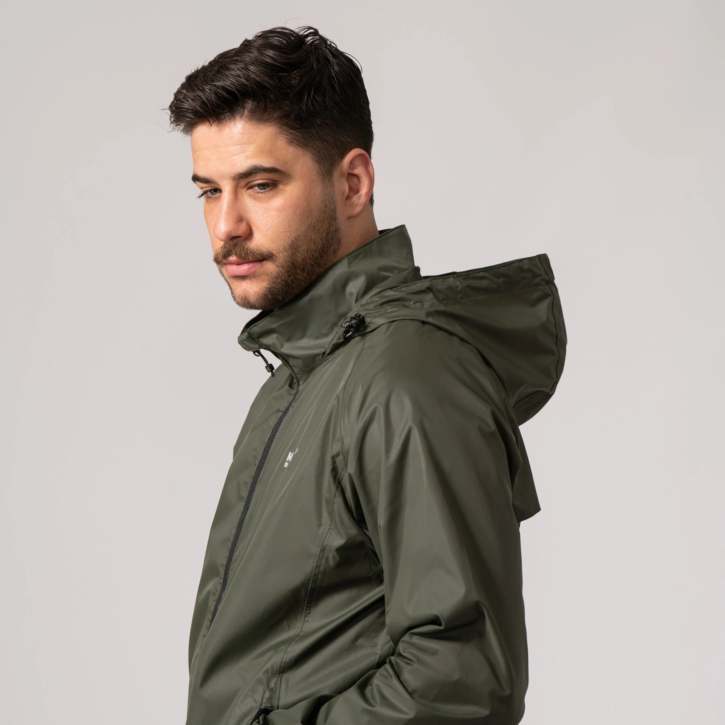 Man wearing a khaki waterproof jacket showing the integrated hood against a plain background
