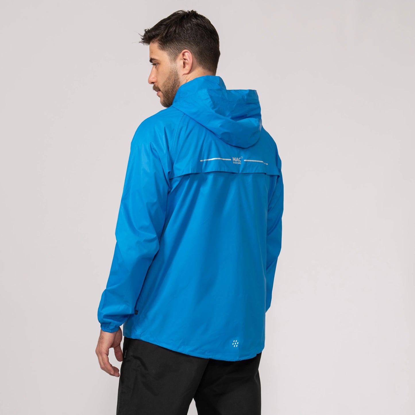 Man wearing a blue waterproof jacket showing the back length on a gray background