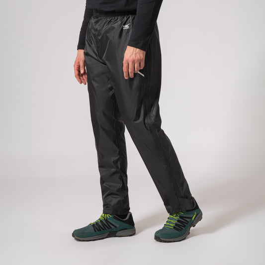 black waterproof overtrousers walking to the left with a white background
