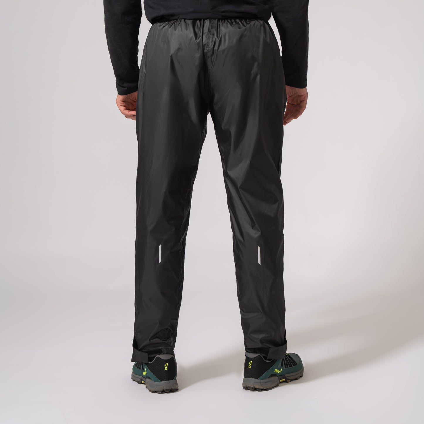 black waterproof overtrousers showing the shape from the back with a white background 