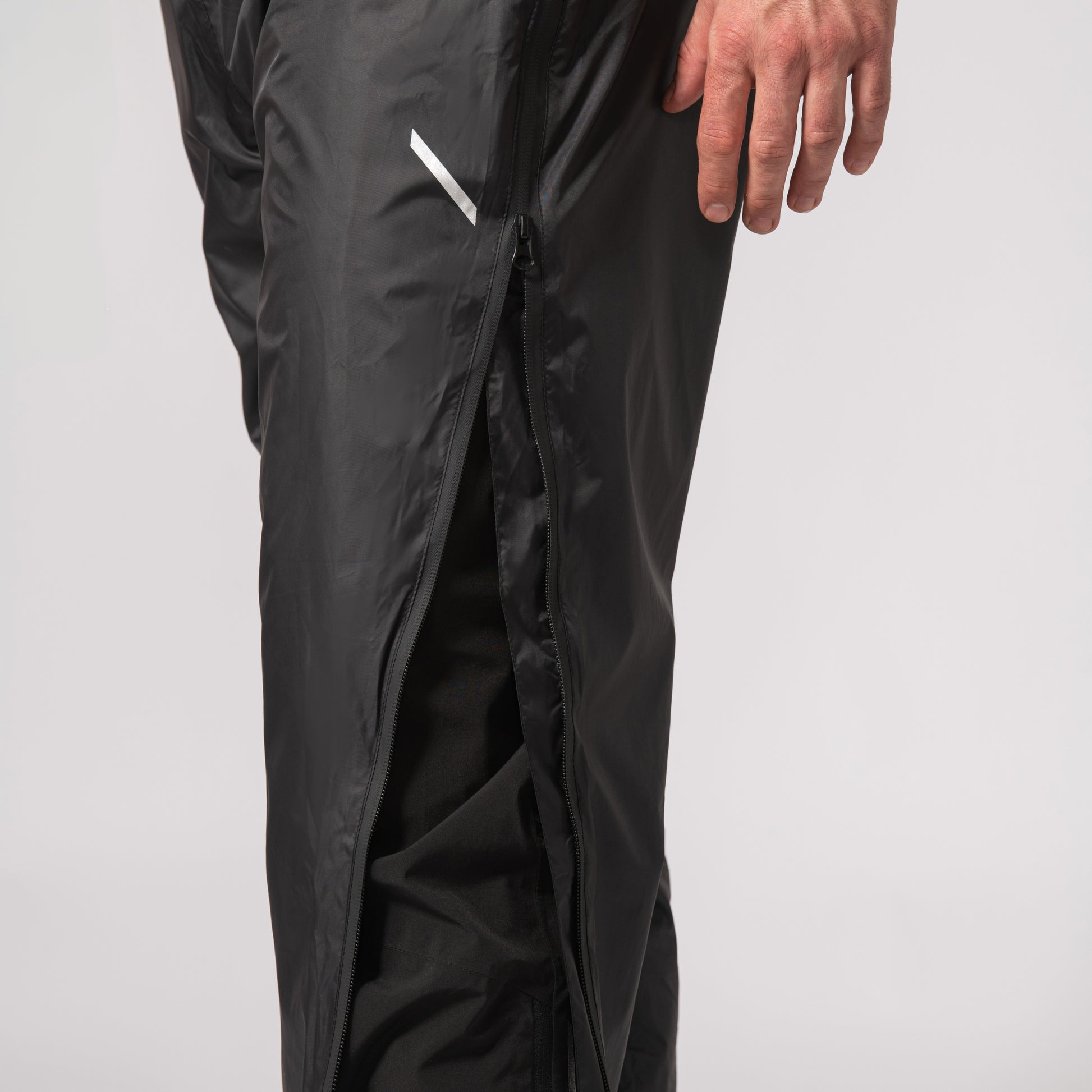 black waterproof overtrousers displaying the full two-way zip with a white background
